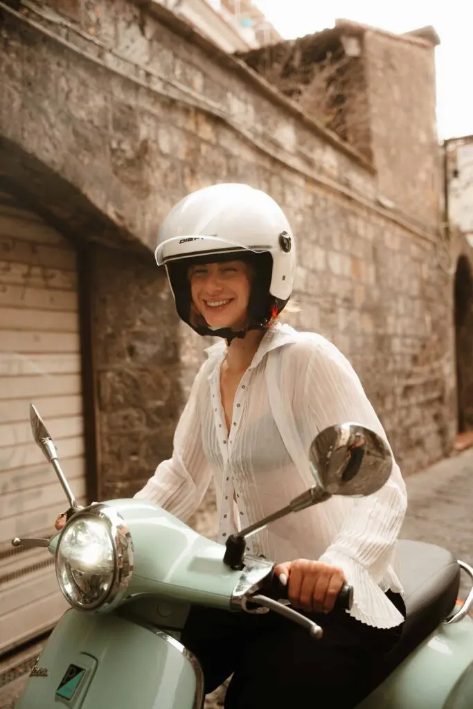 femme casquée souriant sur une Vespa vert menthe à Amalfi