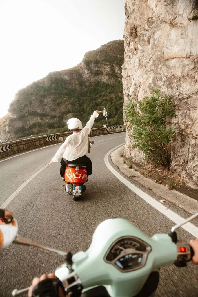 personne sur un scooter orange roulant sur une route côtière de la côte amalfitaine
