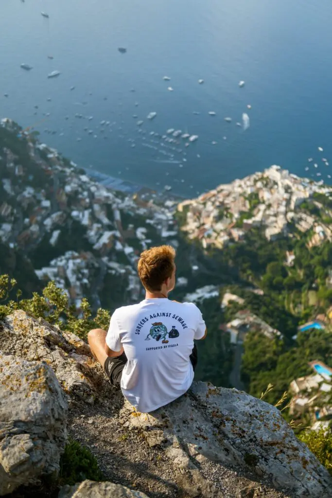 homme sur une falaise surplombant Positano, sur la côte amalfitaine