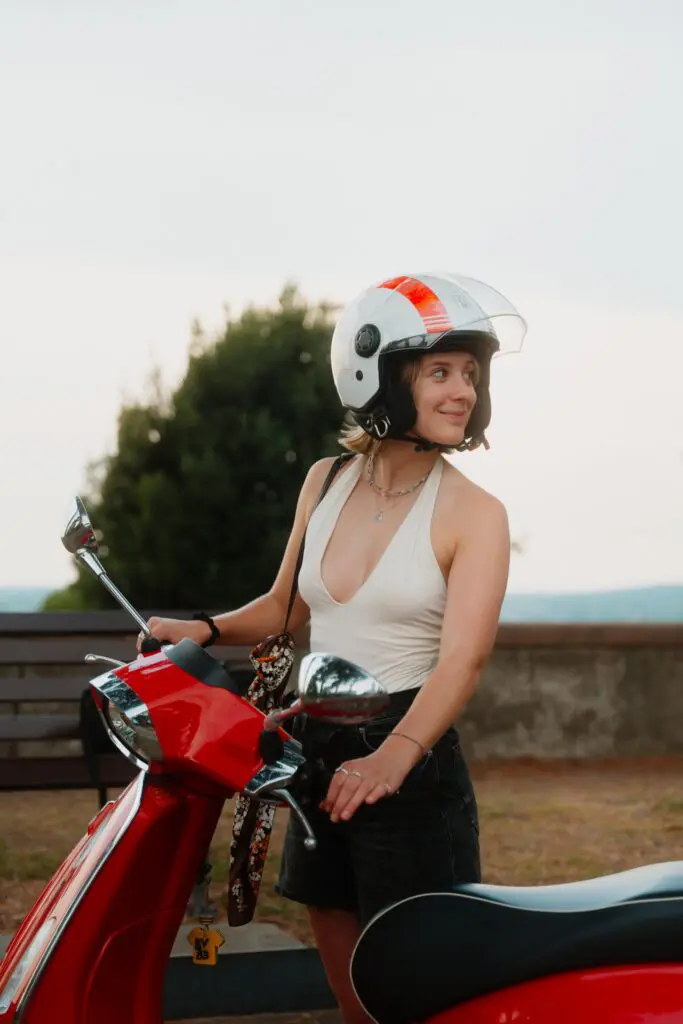 jeune femme casquée sur un scooter Vespa rouge