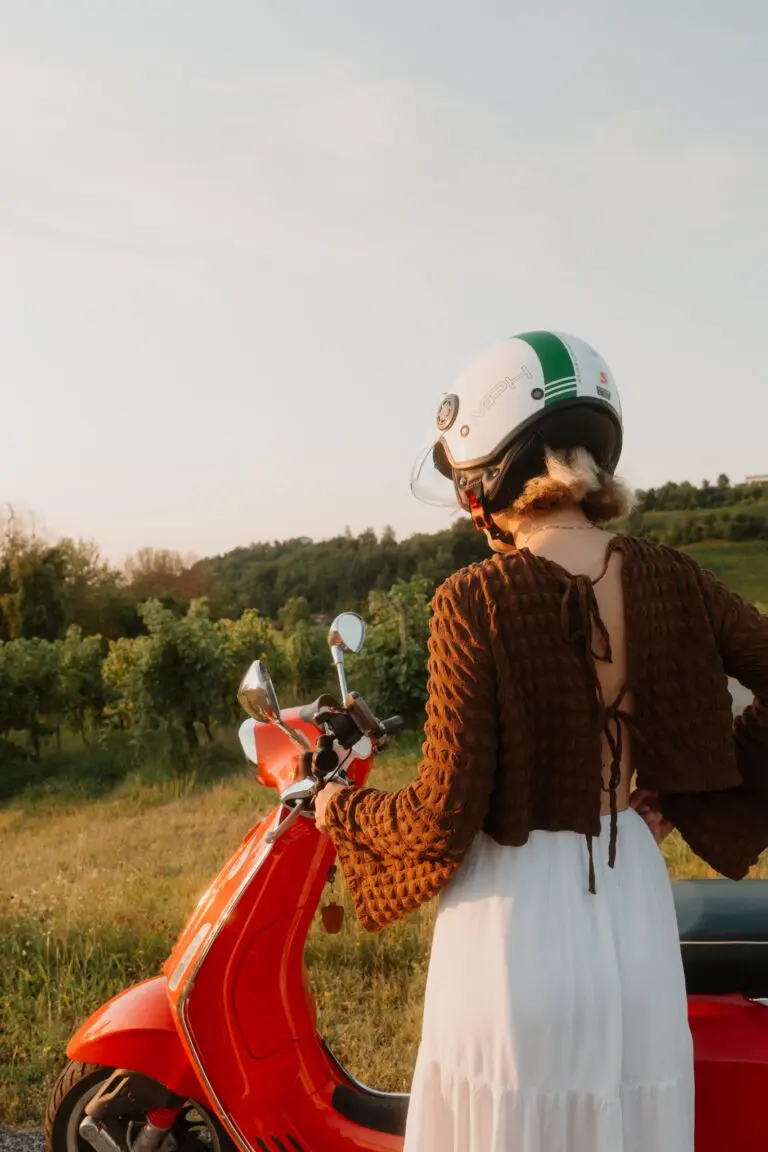 woman in helmet with red vespa in veneto vineyard at sunset