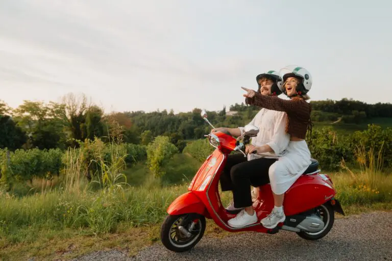 couple conduisant une Vespa rouge à travers les vignobles de Vénétie au coucher du soleil