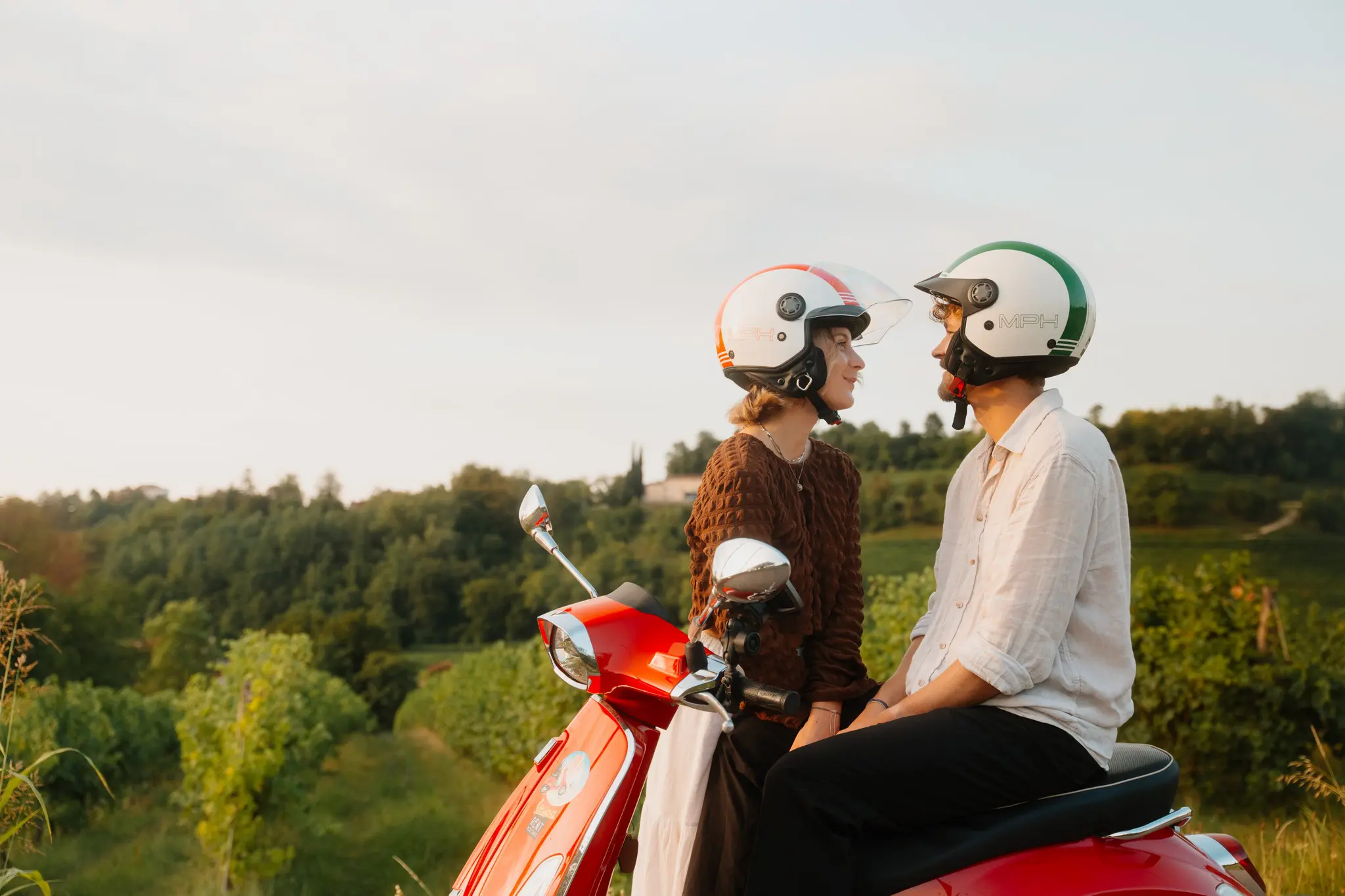 couple on red vespa looking at each other in Veneto vineyard