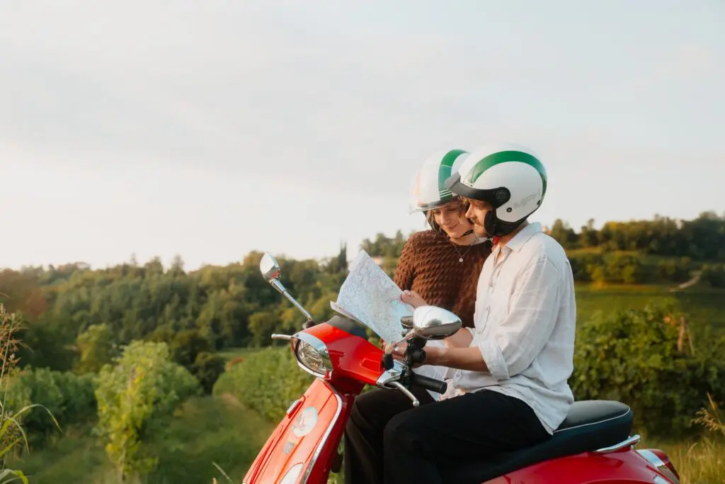 couple on red vespa scooter looking at map in veneto