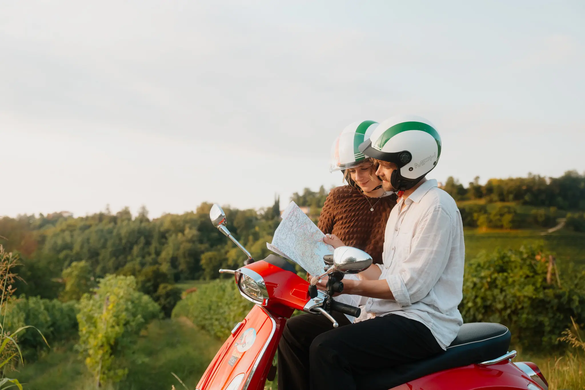 couple on red vespa scooter looking at map in veneto