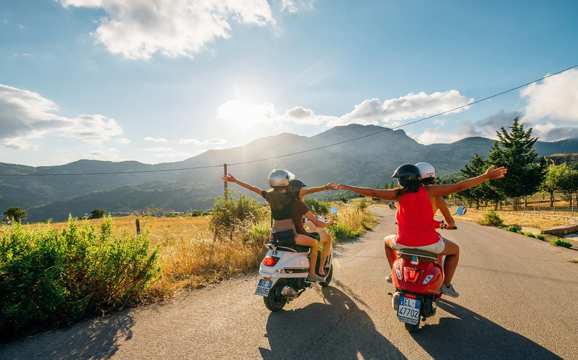 amis roulant en scooter Vespa sur une route pittoresque en Sicile