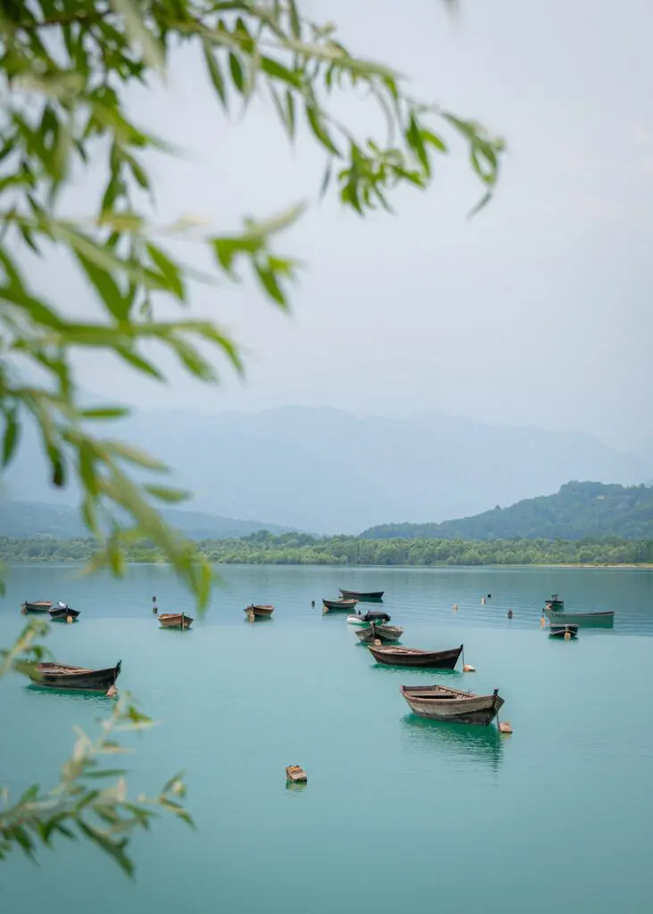 barques en bois sur un lac turquoise entouré de montagnes et d'arbres