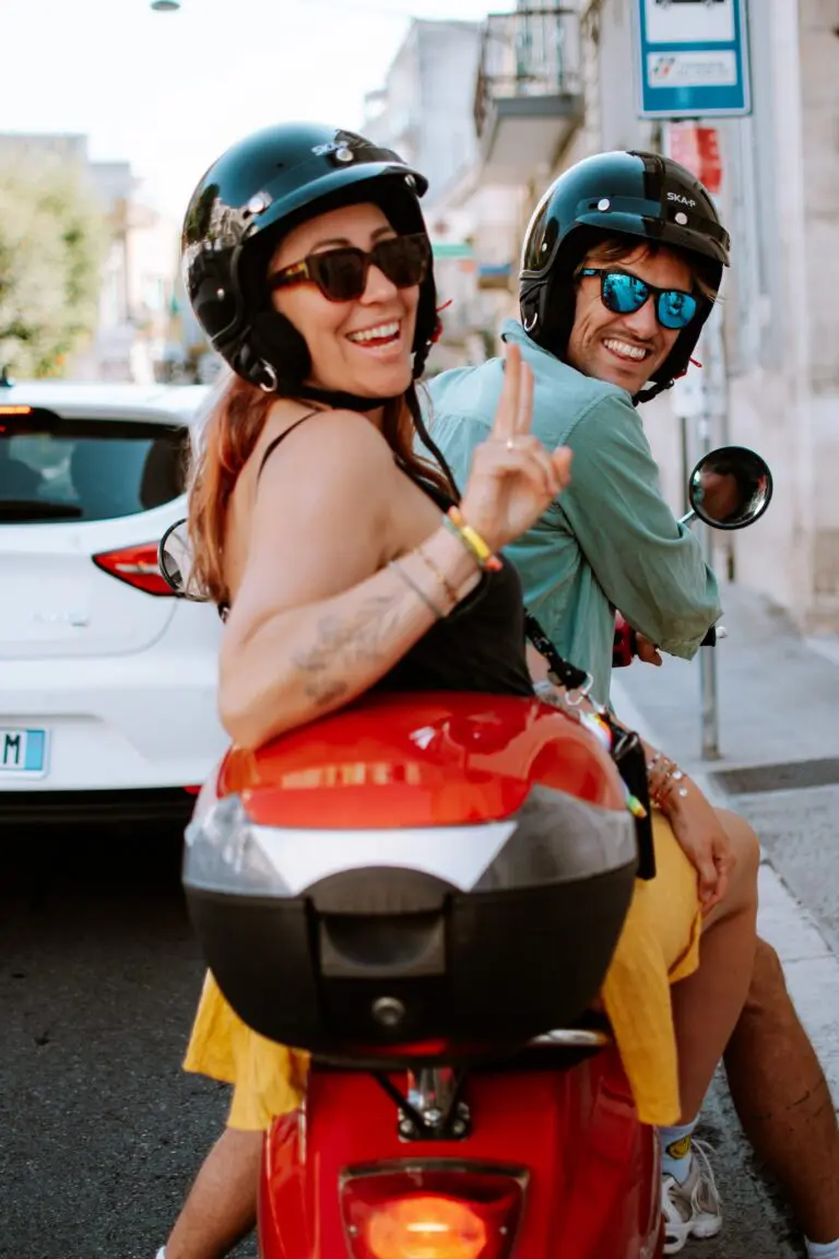 couple souriant sur un scooter rouge dans les Pouilles, en Italie