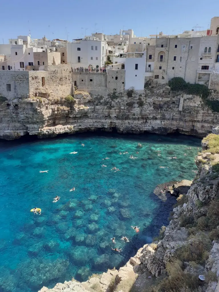 Ville côtière de Polignano a Mare, avec des gens qui se baignent dans une eau turquoise