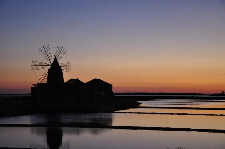 silhouette d'un moulin à vent au coucher du soleil au-dessus des salines de Marsala, en Sicile