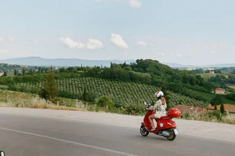 femme à scooter rouge traversant la campagne toscane