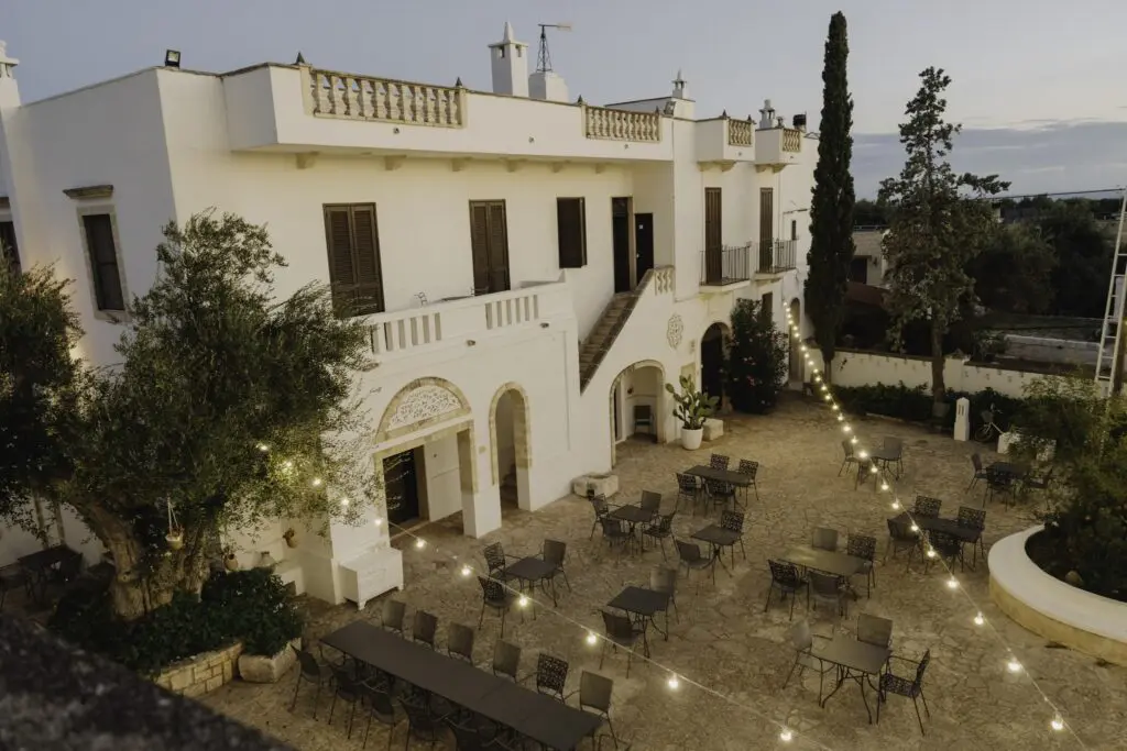 cour intérieure d’un bâtiment blanc, avec guirlandes lumineuses et tables