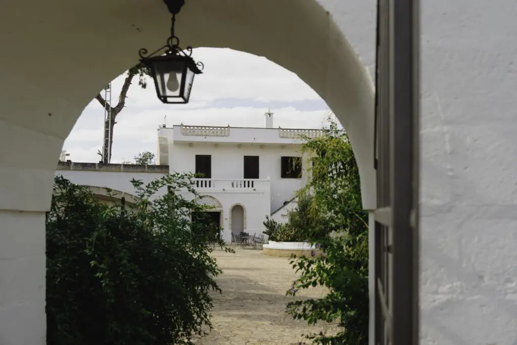 cour intérieure d’un bâtiment blanc avec une arche et une lampe suspendue