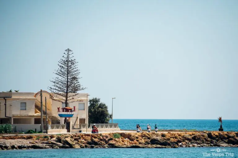 vespa riders on coastal road in Sicily, Italy