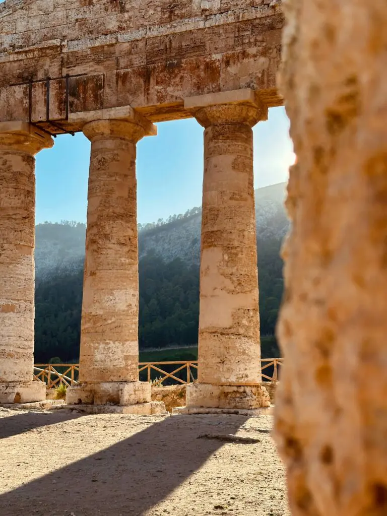 a stone structure with four pillars in front of a mountain