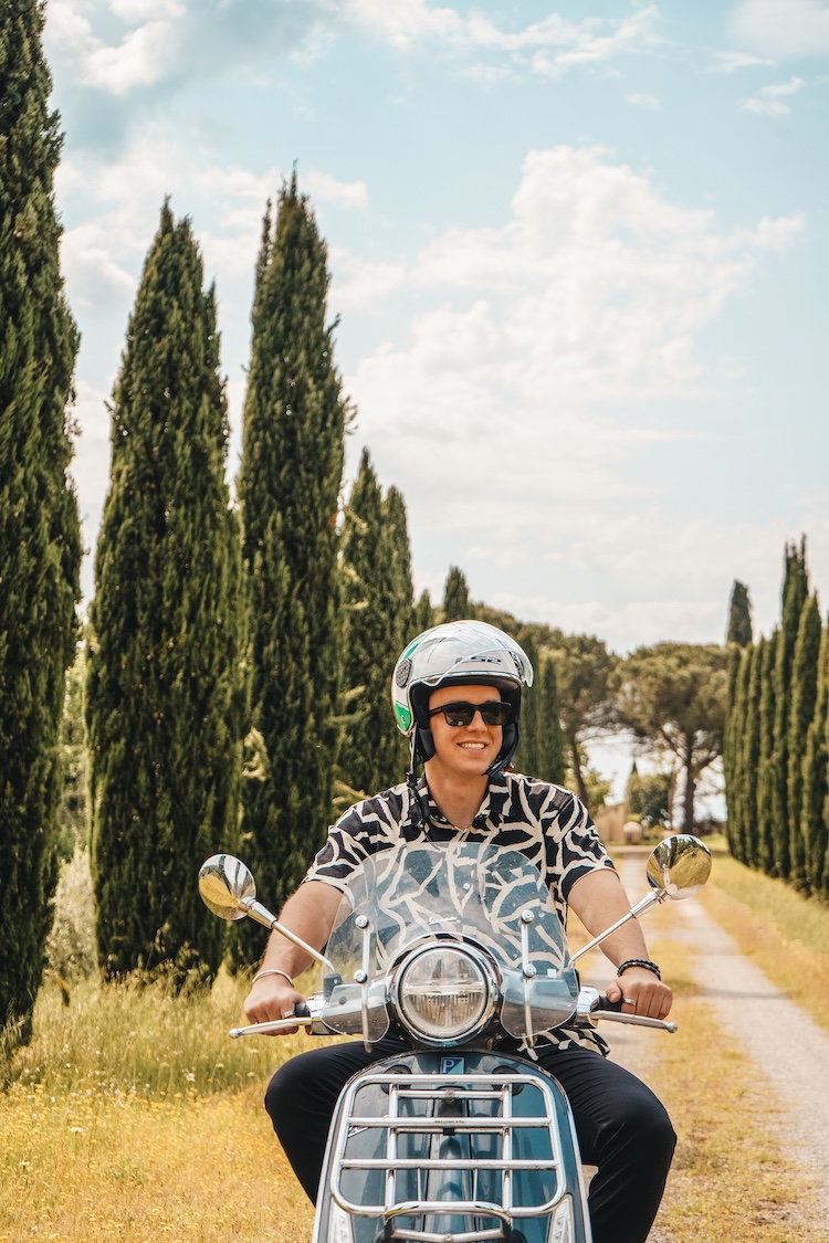 homme sur vespa dans les cyprès de Toscane, conducteur de vespa entre les arbres de cyprès