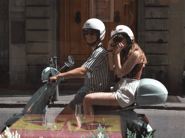 two people on a vespa mirror picture