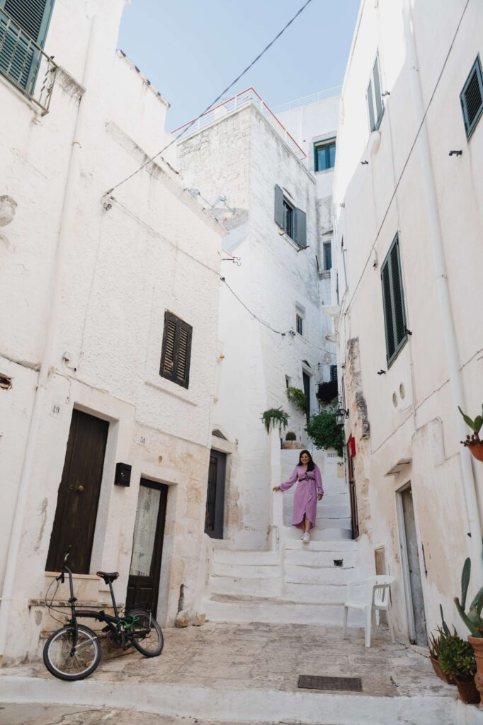 femme marchant sur des escaliers dans la ville blanche d'Ostuni
